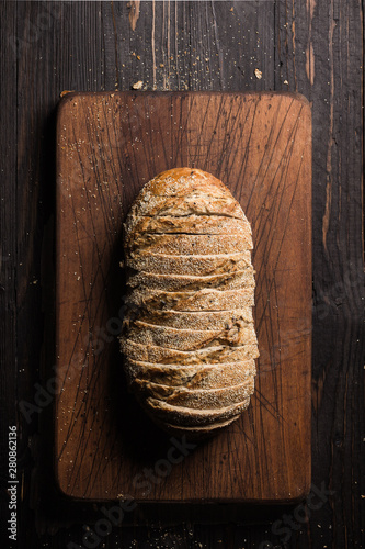 Obraz na plátně Aerial shot of sliced loaf of bread on cutting board