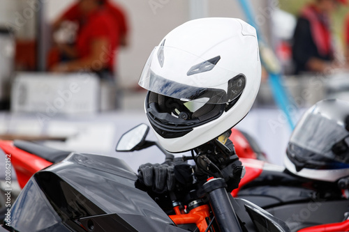 White moto helmet and leather gloves on motorcycle against blurred background