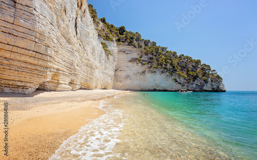 Puglia a touristic destination in Italy - People with kayaks at Faraglioni - Baia dell Zagare - Famous Italian beach with coastal rocks eroded by waves  photo