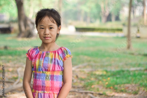 Cute little girl portrait in a summer green park.