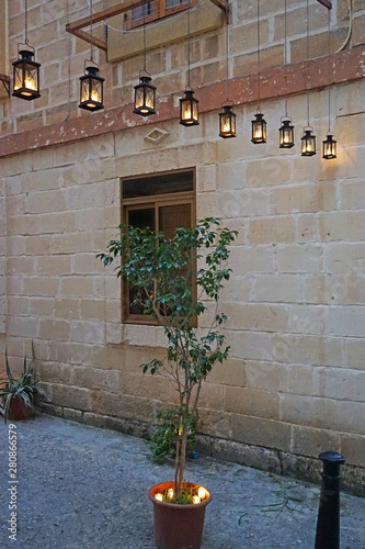 A potted plant and lanterns, the wall of stone house. Preparation for Birgu Fest, Birgu by candlelight. Malta  photo