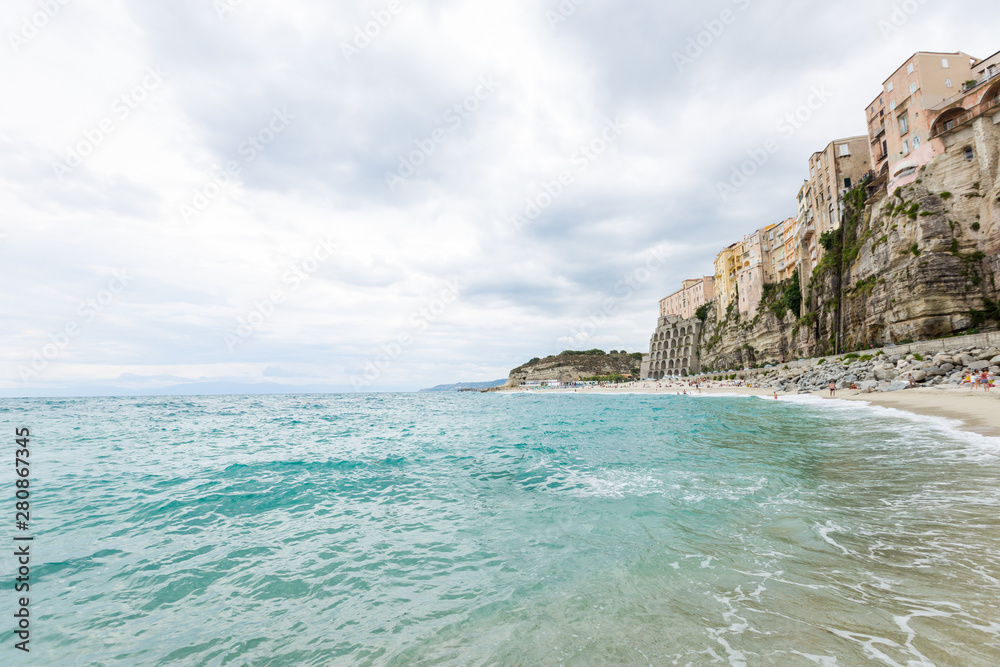 Tropea town and beach coastline of Tyrrhenian Sea with turquoise water, colorful buildings on top of high big rocks, view from Sanctuary church of Santa Maria dell Isola, Calabria, Southern Italy