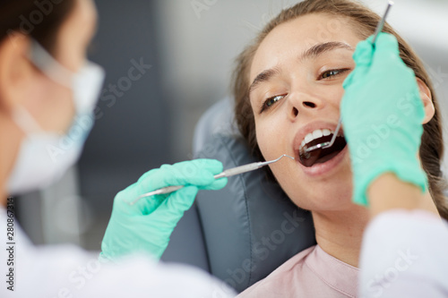 Close up portrait of beautiful young woman in dental chair during medical check up, copy space