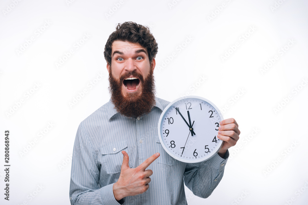 Photo of amazed man screaming and pointing at big watch Photo of amazed man screaming and pointing at big watch
