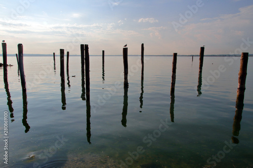 lago di garda con pali di legno e riflessi nell'acqua