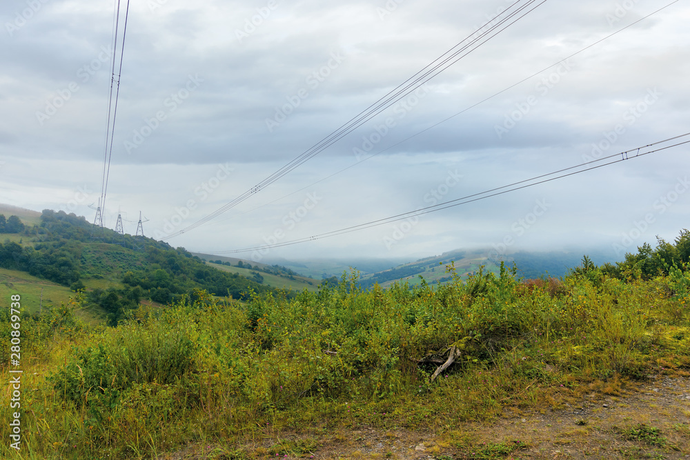 high voltage power lines tower in mountains.  energy delivery background. efficient electricity delivery concept. hazy weather with overcast sky