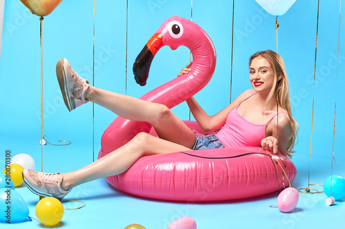 sexy blonde girl in stylish pink top, shorts and trainers lying with raised legs on the mattress. full length photo. joy concept © alfa27