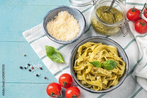 Pasta with pesto sauce, cooking concept, ingredients and spices on a table with a dish. Top view, copy space. Vegetarian food.