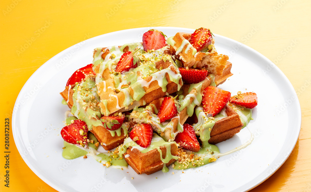 Belgian waffles with pistachio cream topping and strawberries Belgian waffles with pistachio cream topping and strawberries