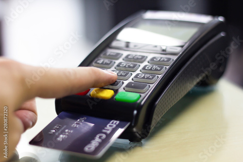 Hand press pin processed on credit card machine in store, close up.