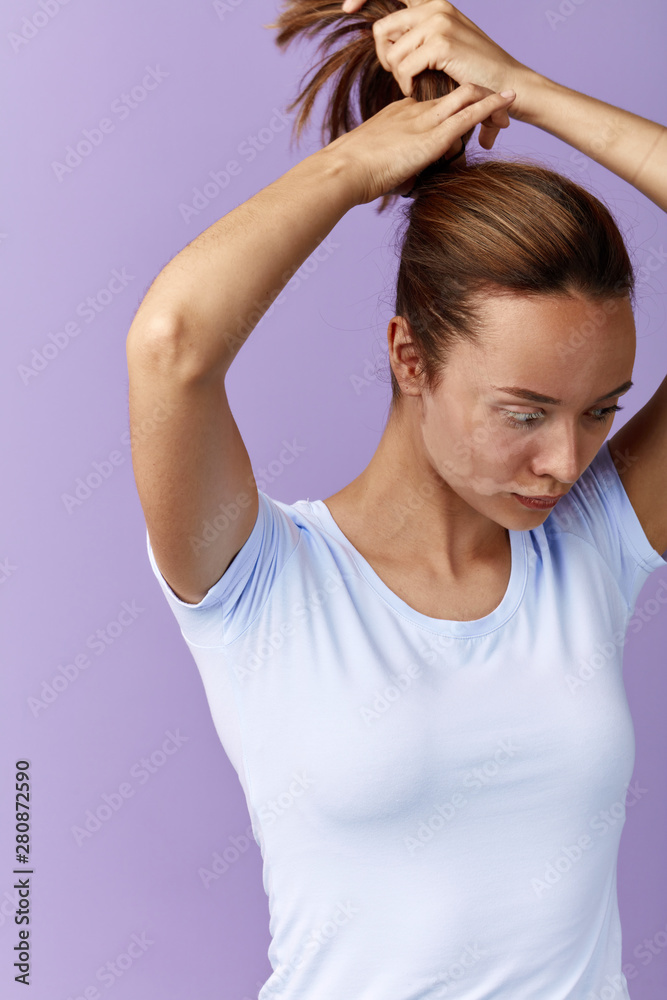 young woman doing style hair, hairdo, girl making a ponytail. close up side view photo. preparation for treatment, surgery , isolated blue background, studio shot young woman doing style hair, hairdo, girl making a ponytail. close up side view photo. preparation for treatment, surgery , isolated blue background, studio shot