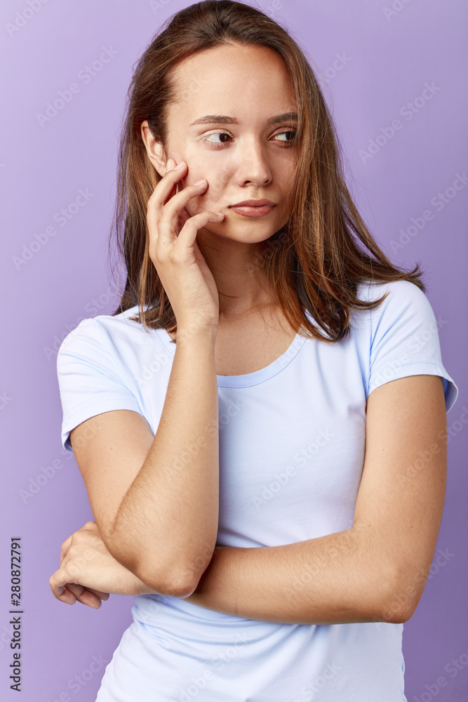 serious depressed girl with a palm on her cheek looking aside thinking about cleaning her face . close up portrait,