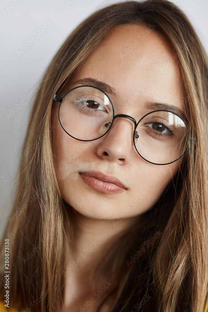headshot of brown-haired girl looking at the camera, beauty concept. wellness, wellbeing, student in eyeglasses