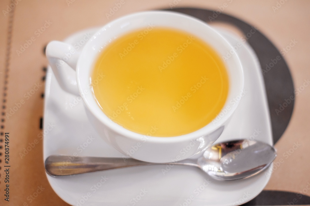 A white Cup of herbal tea on a saucer on a table in a cafe. A white Cup of herbal tea on a saucer on a table in a cafe.