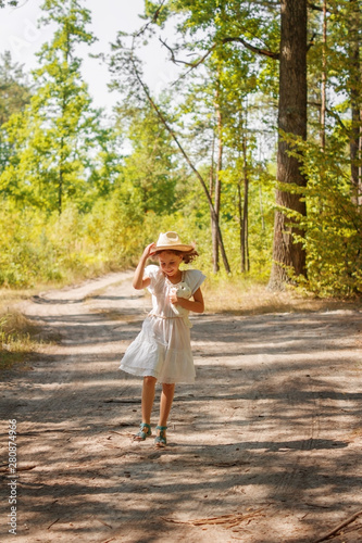 Girl child a white dress running in a summer forest.