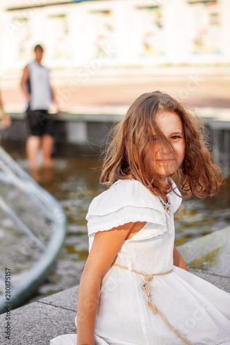Child girl near the city fountain