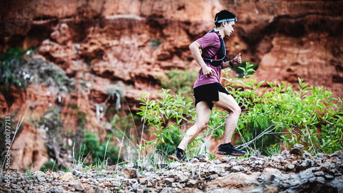 trail runner running on the rocky road in the morning