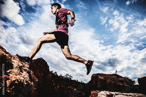 Obraz na plátně trail runner jumping on the horizon and stone