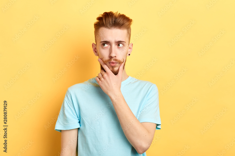 thoughtful pensive serious man who looks aside touching his chin and making up a plan, thinking about the pluses and minuses of the offer isolated on yellow background. studio shot thoughtful pensive serious man who looks aside touching his chin and making up a plan, thinking about the pluses and minuses of the offer isolated on yellow background. studio shot