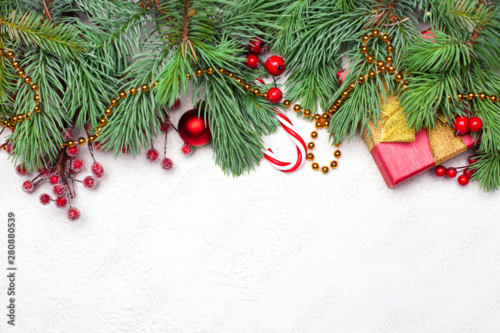 Christmas composition. Border made of green Xmas fir branch, red holly berries and baubles on white texture stucco plaster background. Flat lay, top view with copy space Christmas composition. Border made of green Xmas fir branch, red holly berries and baubles on white texture stucco plaster background. Flat lay, top view with copy space
