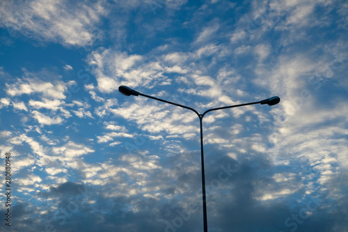 Blue sky background with clouds and silhouette of electric pole