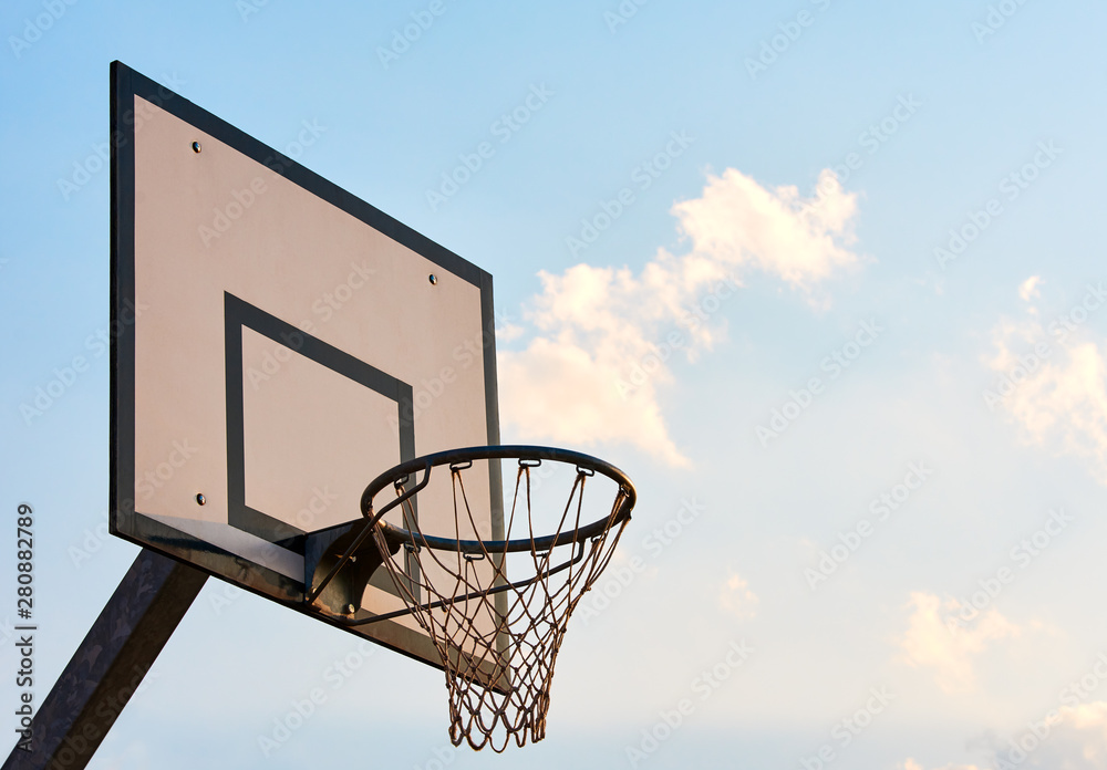 view of board with basketball hoop and net. Evening sky at sunset.
