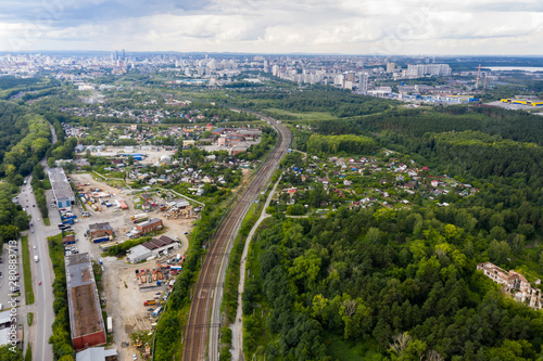 The city skyline in the distance in foreground, railway, industrial area and a forest with houses. Yekaterinburg, Russia © vladimircaribb