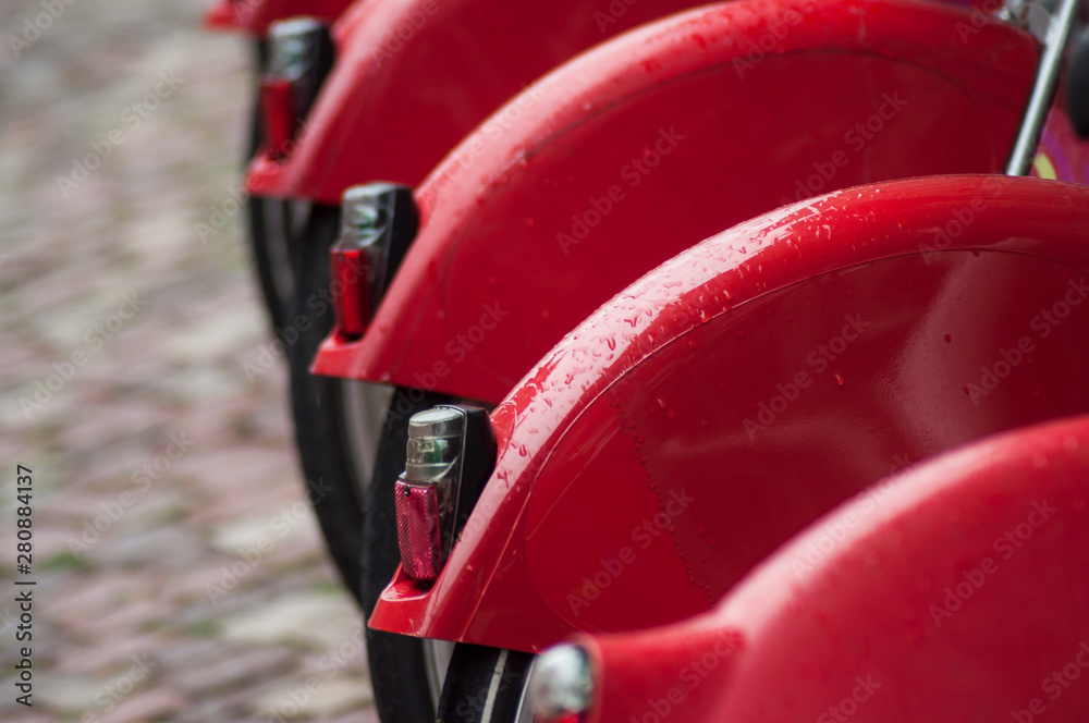 Closeup of rain drops on red city bicycle on cobblelstone background Closeup of rain drops on red city bicycle on cobblelstone background