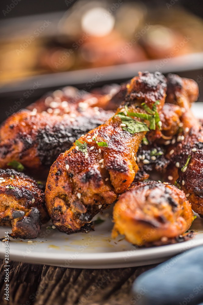 Grilled hicken legs BBQ with spices herbs and sesame on baked paper. Roasted poultry meal on white plate Grilled hicken legs BBQ with spices herbs and sesame on baked paper. Roasted poultry meal on white plate