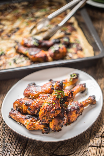 Grilled hicken legs BBQ with spices herbs and sesame on baked paper. Roasted poultry meal on white plate