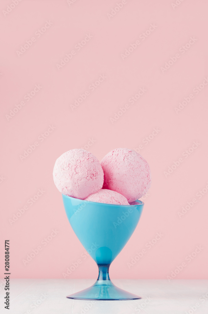 Summer cold dessert - three pink strawberry ice cream balls in elegant blue bowl on white wood table and pastel pink wall, vertical. Summer cold dessert - three pink strawberry ice cream balls in elegant blue bowl on white wood table and pastel pink wall, vertical.