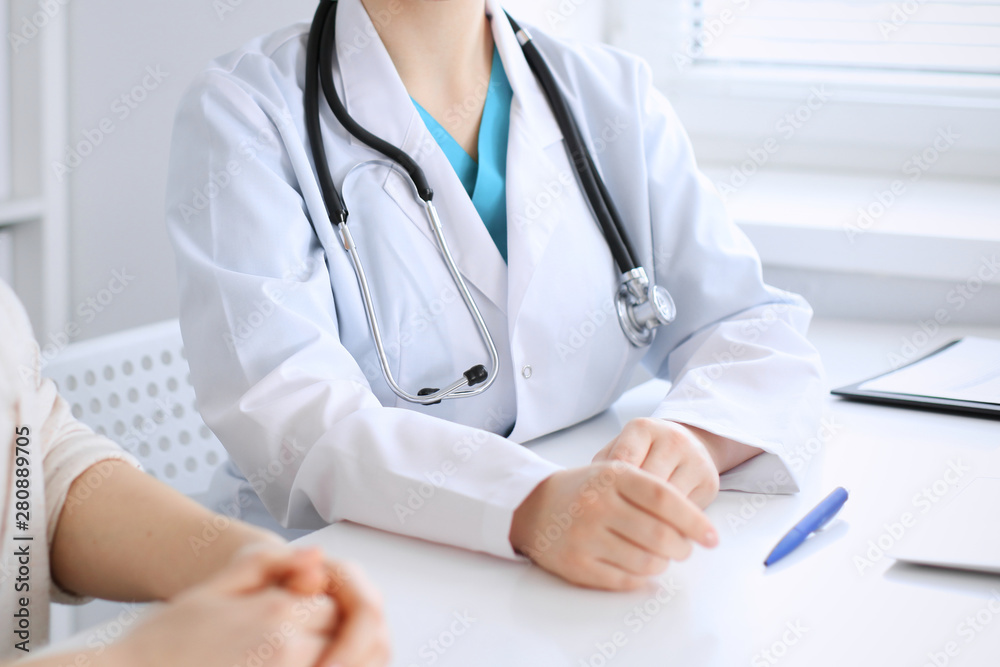 Doctor and patient discussing something while sitting at the desk at hospital, close-up. Medicine and health care Doctor and patient discussing something while sitting at the desk at hospital, close-up. Medicine and health care