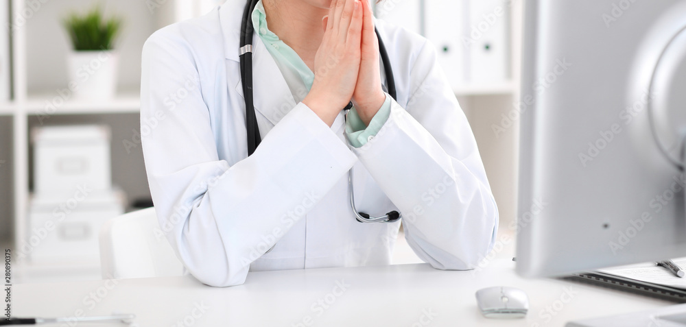 Doctor woman sitting at the desk with computer at workplace in hospital office. Unknown physician's hands close-up. Green tone of blouse. Medicine and health care concept Doctor woman sitting at the desk with computer at workplace in hospital office. Unknown physician's hands close-up. Green tone of blouse. Medicine and health care concept