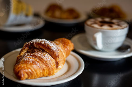 Typical italian breakfast with chocolate croissant and cappuccino 