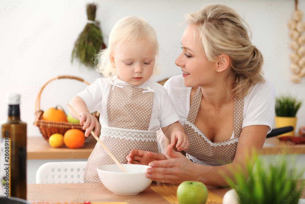Happy mother and little daughter cooking in kitchen. Spending time all together, family fun concept Happy mother and little daughter cooking in kitchen. Spending time all together, family fun concept