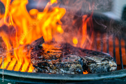 Tableau sur toile Grilling steaks on flaming grill