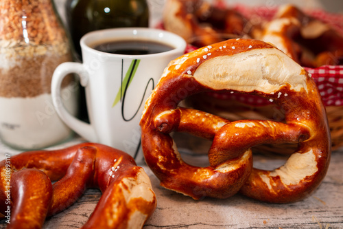 Brezel und Kaffee - zwei Brezeln auf einem gedeckten Tisch mit einer Tasse Kaffee - Salzbrezelbrezel - Salz