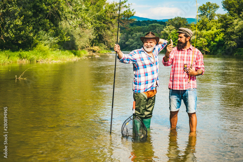 Fly angler on the river. Fishing in river. Fishing in river. Fly fisherman using fly fishing rod in beautiful river. Father and son fishing.