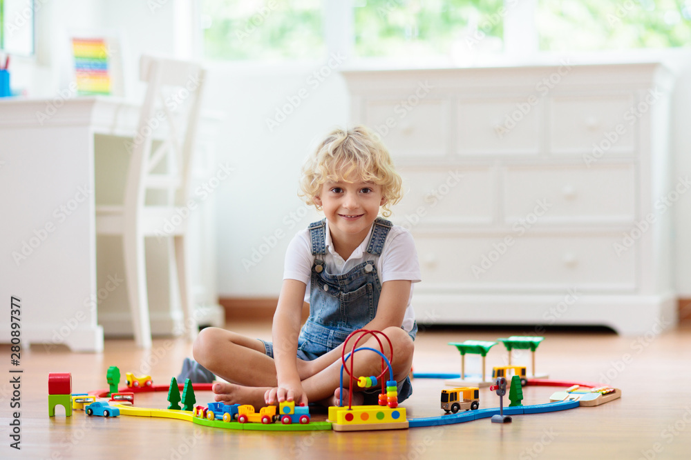 Kids play wooden railway. Child with toy train.