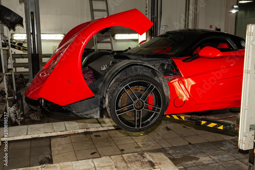 Фотография Red sports car raised on a lift in a car repair shop, rear bumper and spoiler