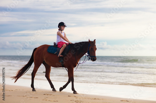 Kids riding horse on beach. Children ride horses.