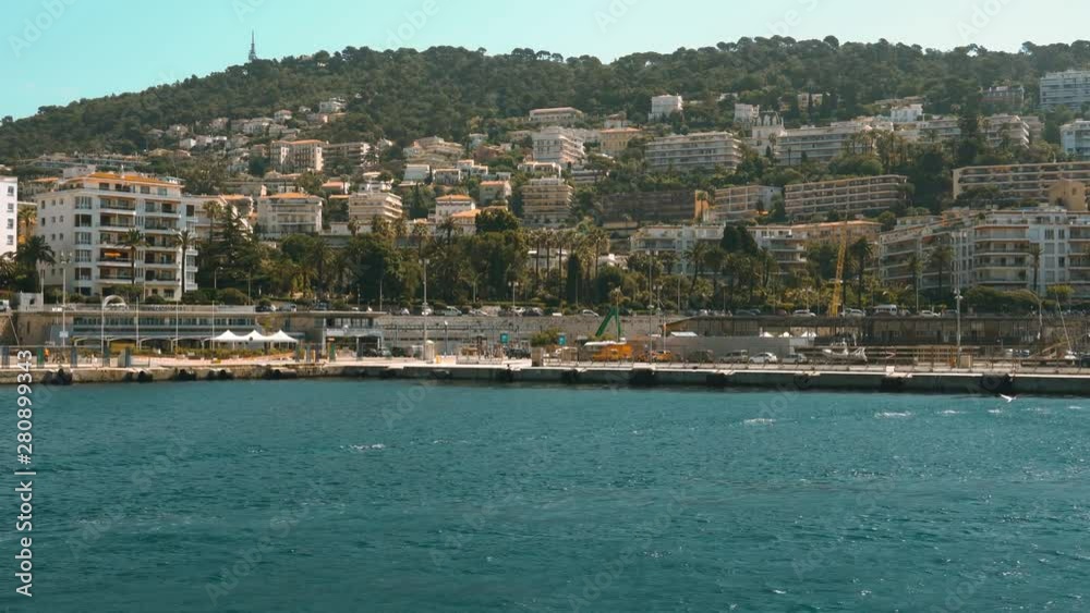 Port in France.  Mountains., trees, sea and buildings.