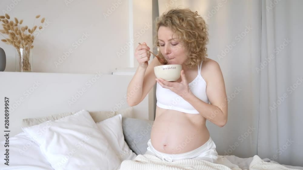 Funny Hungry Pregnant Woman Eating Cereals For Breakfast In Bed. Pregnancy Cravings Concept. Funny Hungry Pregnant Woman Eating Cereals For Breakfast In Bed. Pregnancy Cravings Concept.
