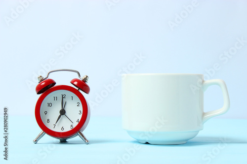 alarm clock on a colored background, a cup of coffee and stationery