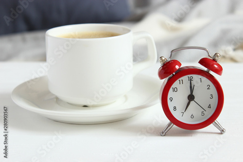 Alarm clock and cup of coffee in the room interior