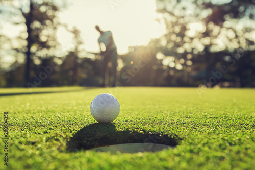 golf player putting golf ball into hole