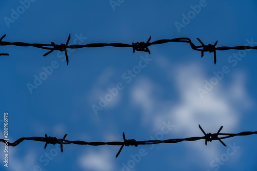 Barbed wire. Barbed wire on fence with blue sky to feel worrying. 