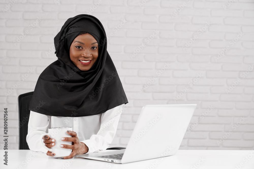 African female office worker in black hijab posing. African female office worker in black hijab posing.