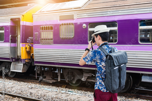 Concept life style holidays travel or journey : Young Asian backpacker man is take a photo at the train station.