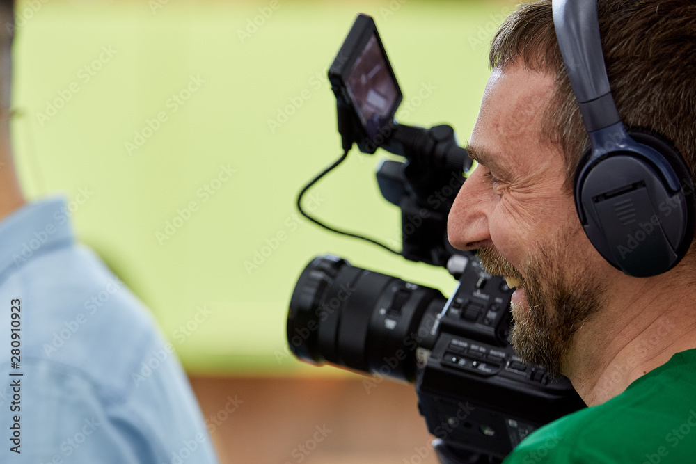 Videographer shooting a film or a television program in a studio with a professional camera, backstage Videographer shooting a film or a television program in a studio with a professional camera, backstage
